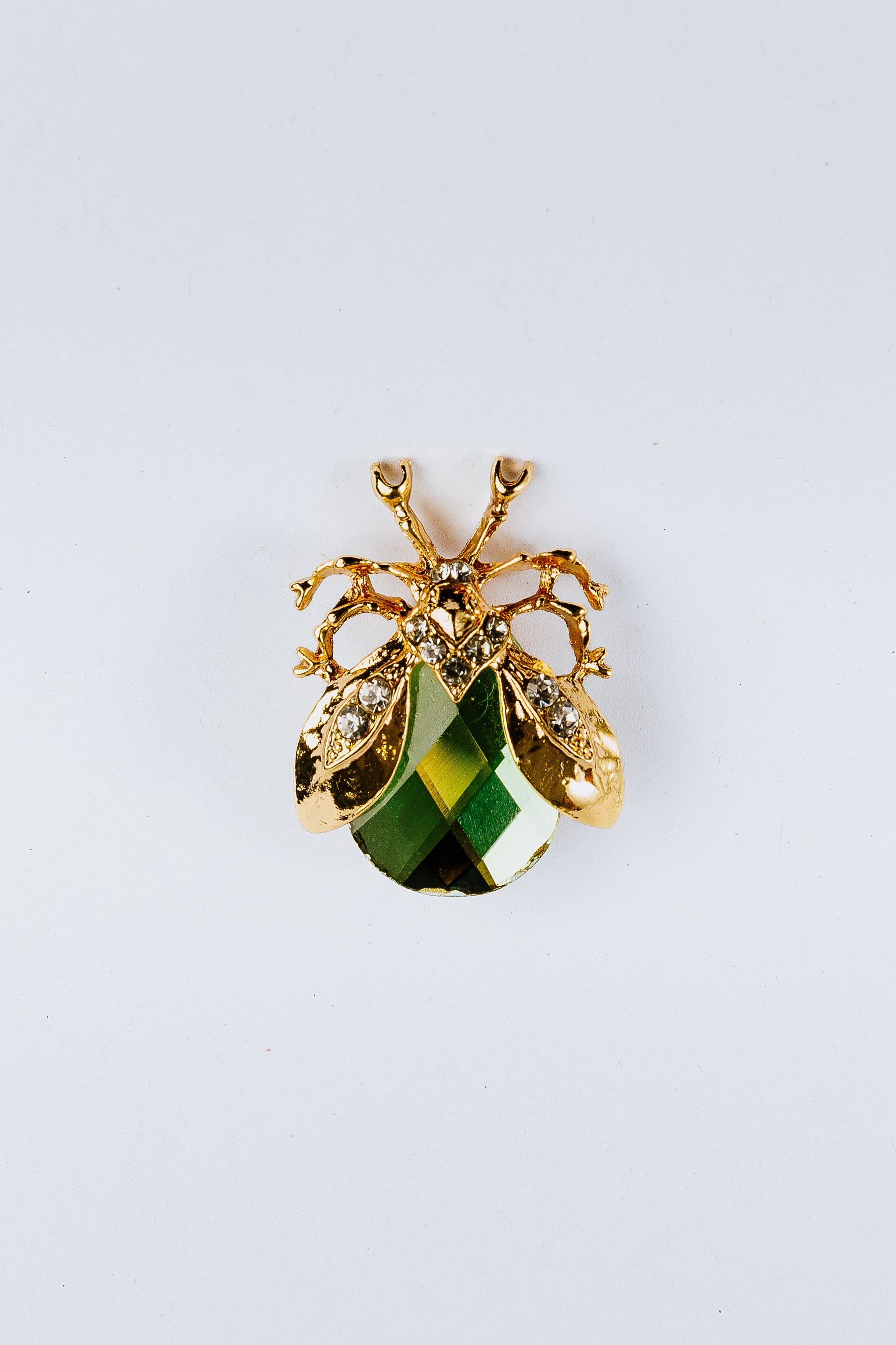 Beetle charm with a green gemstone on a white background
