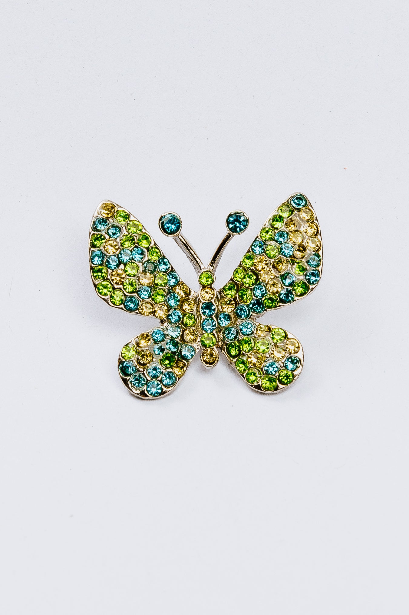 Butterfly-shaped charm with gemstones on a white background