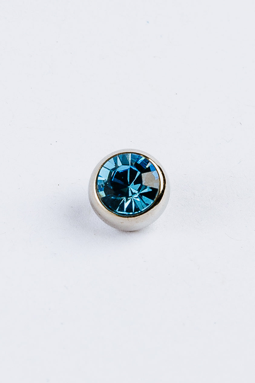 Blue gemstone in a silver setting on a white background