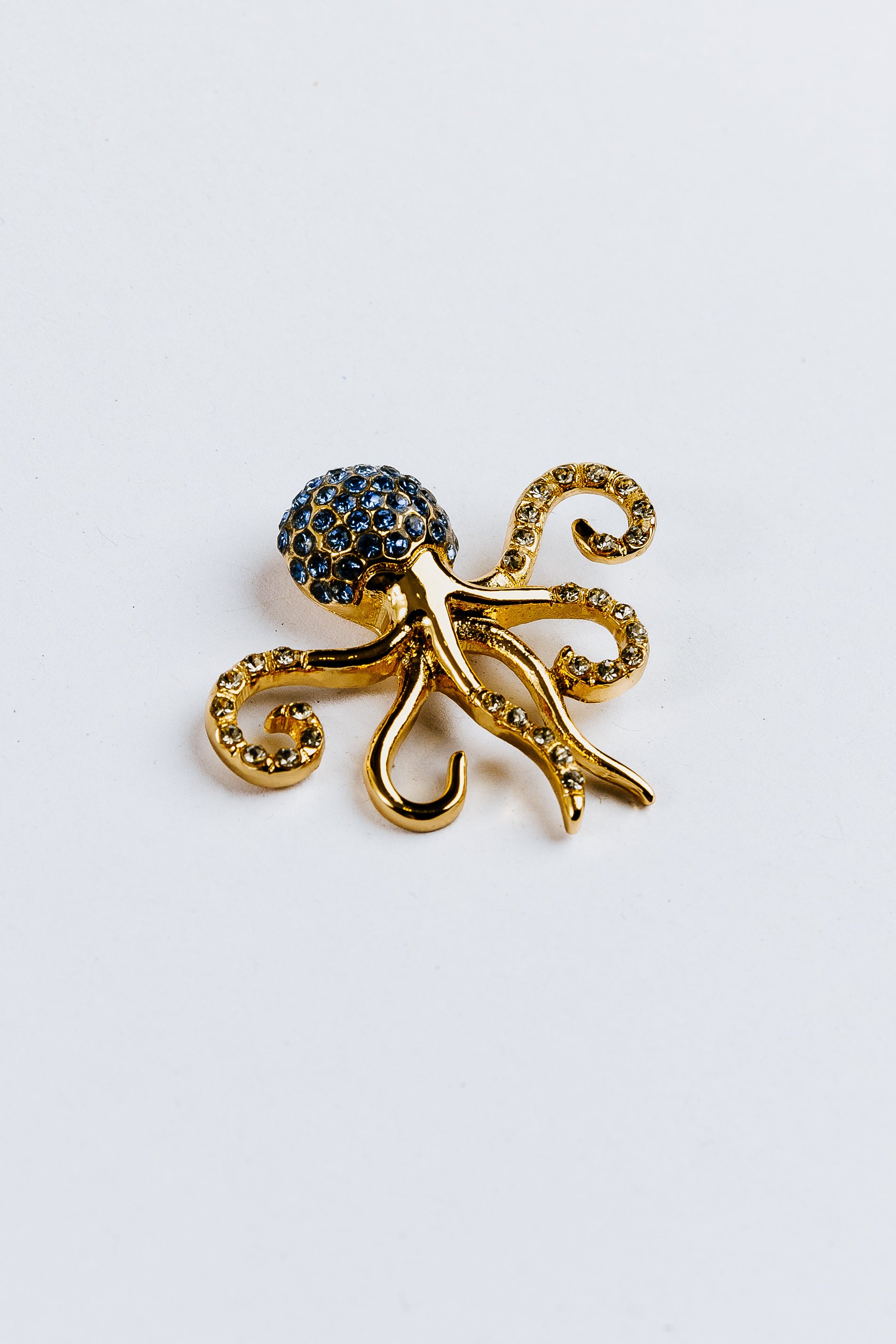 Gold octopus charm with gemstones on a white background