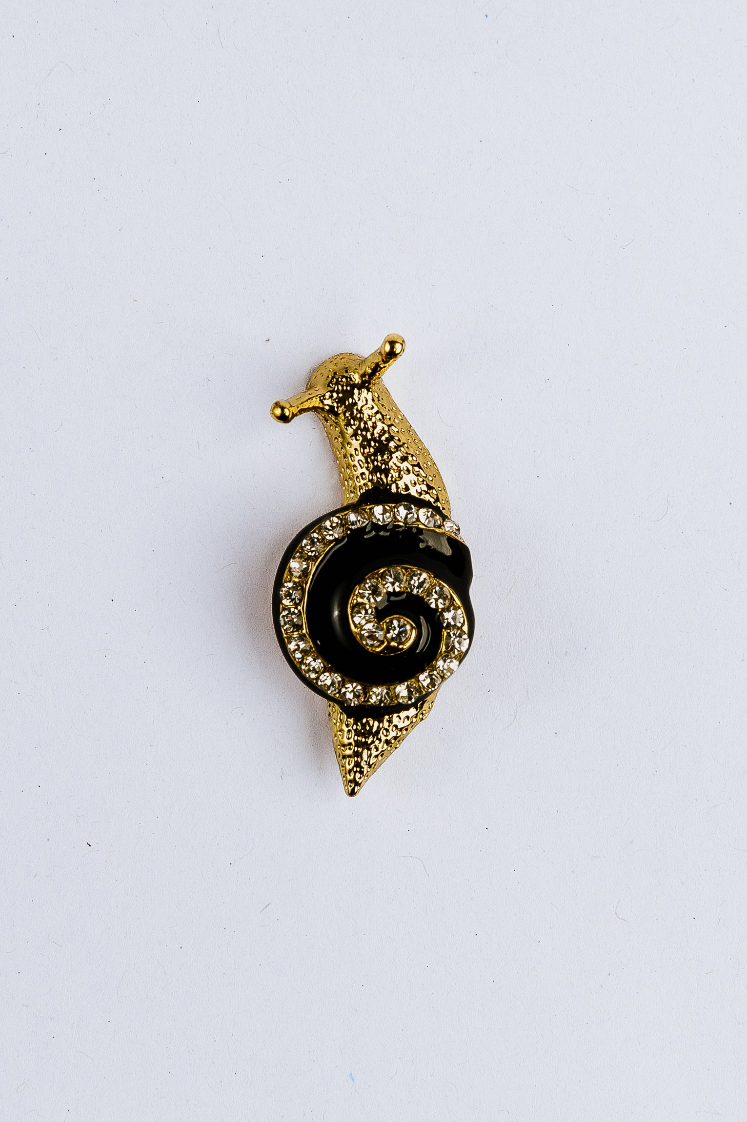 Gold and black spiral brooch on a white background