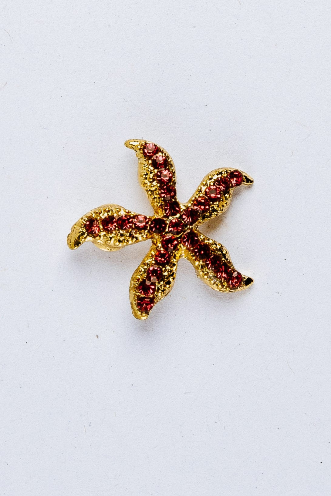 Gold and red starfish-shaped charm on a white background