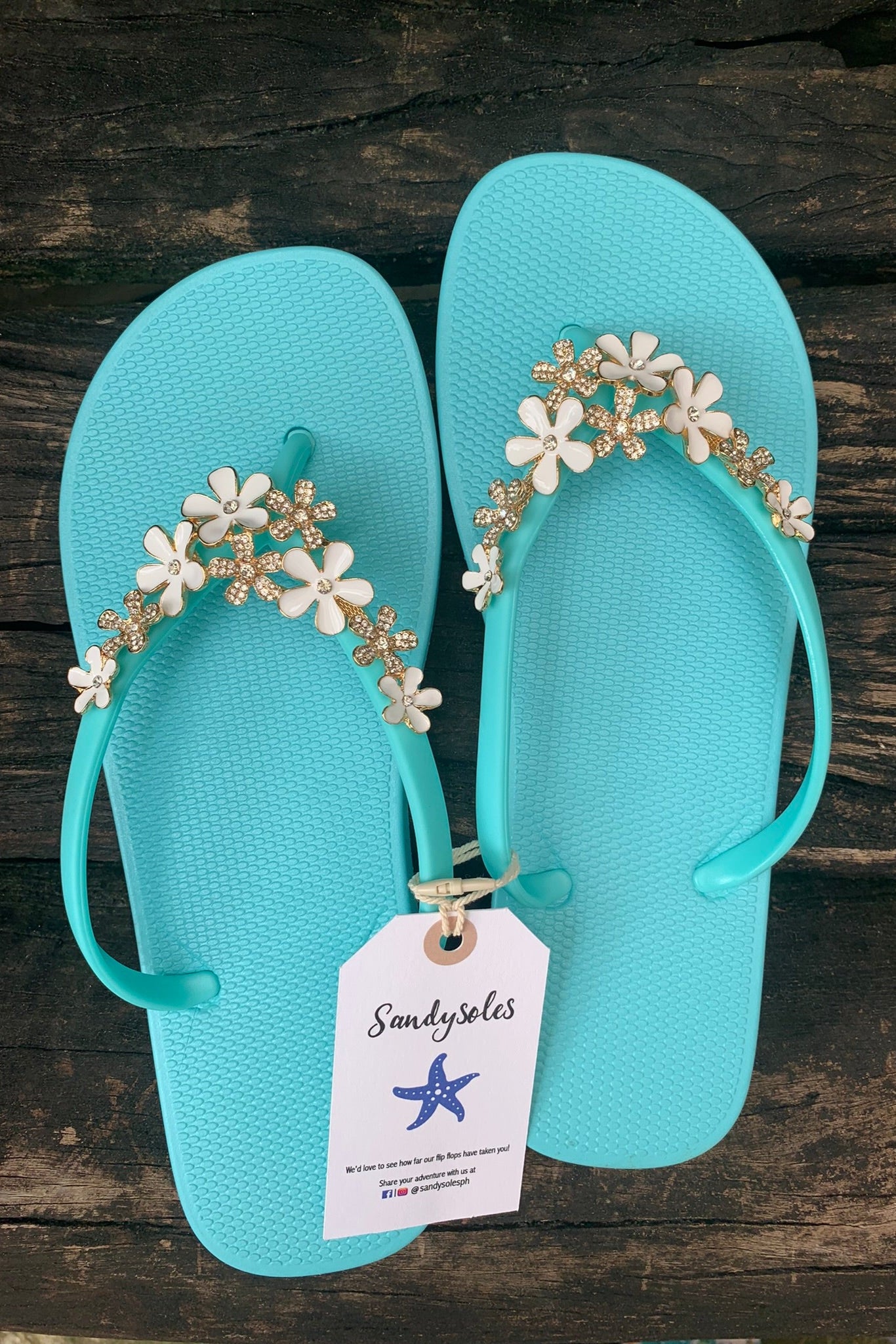 a pair of aqua flipflops with blue flower arch design charm with rhinestones
