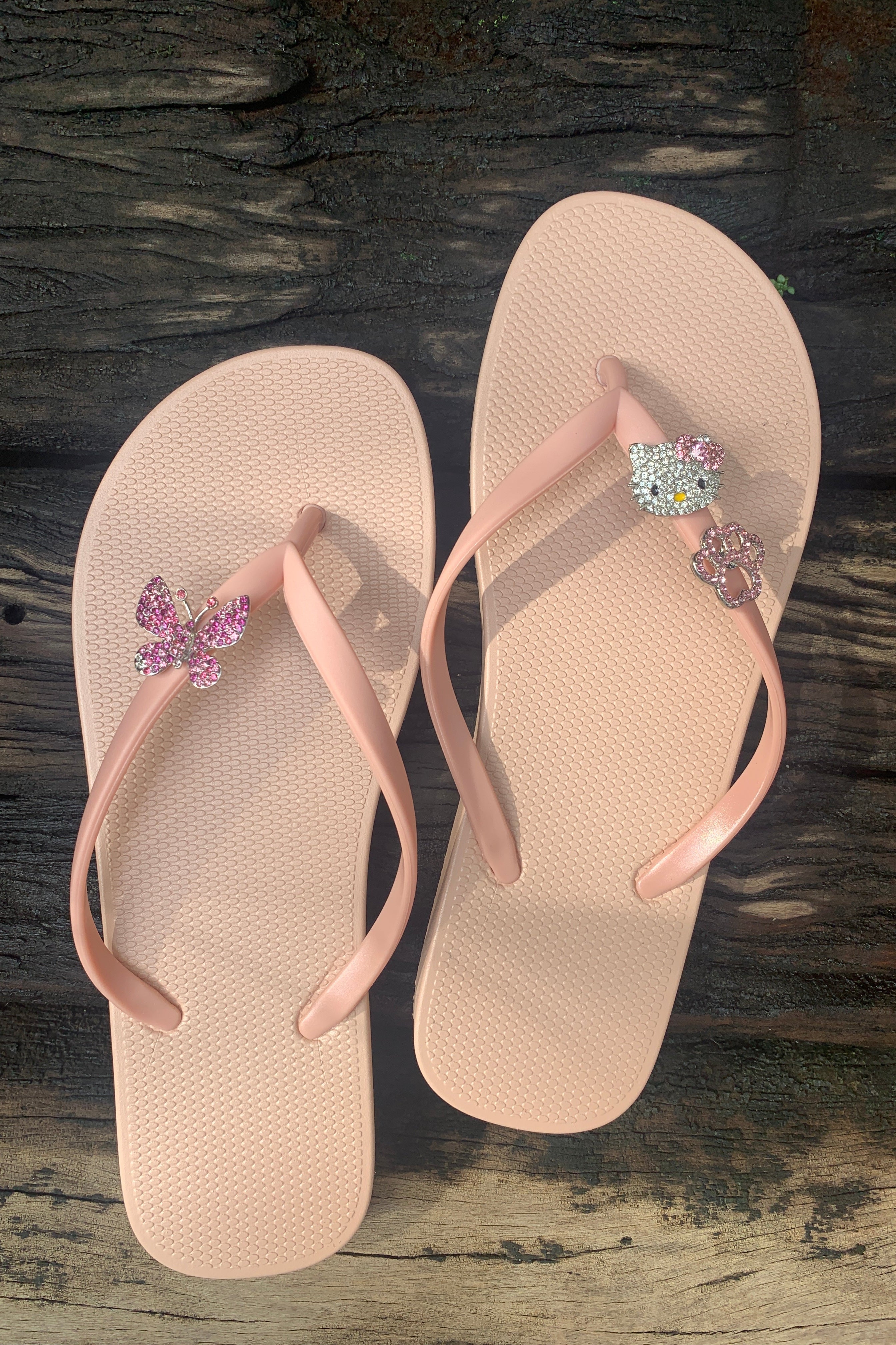 Pair of beige and rose flip-flops with butterfly, hello kitty and dog paw decorative charms
