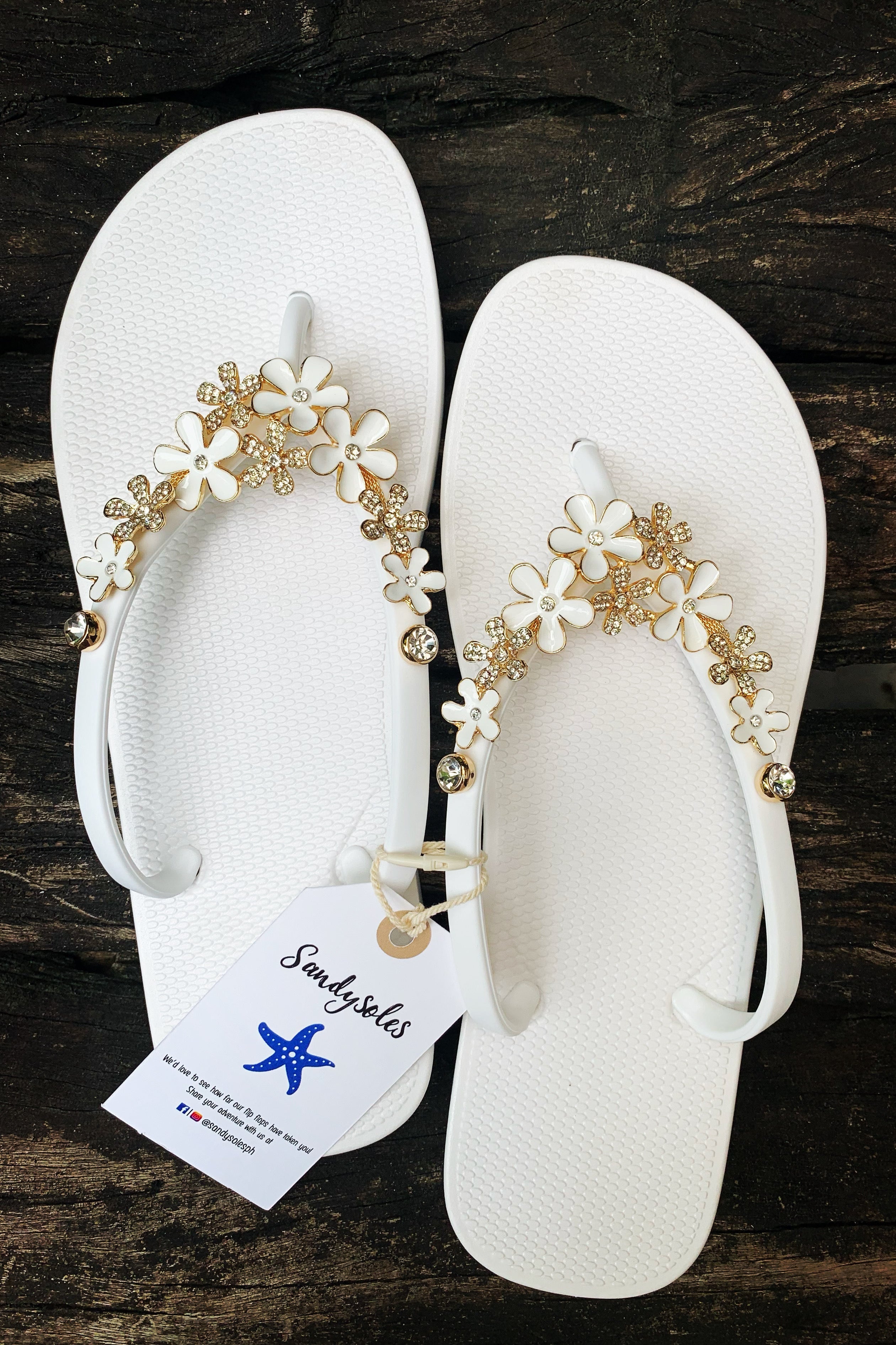 white flip-flops with white flower arch-shaped charm with gemstonesa