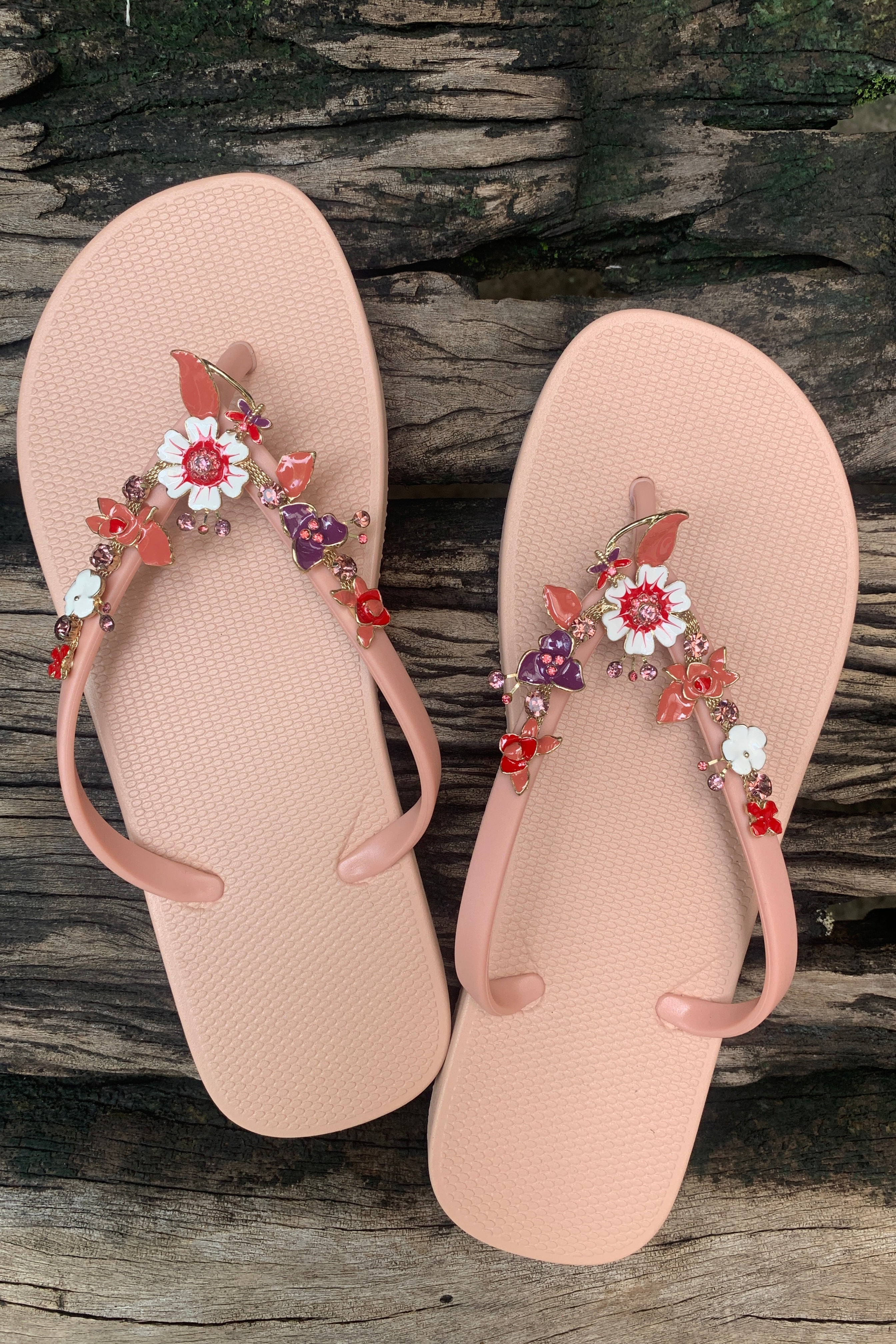 a pair of pink flipflops with red flower arch design charm with rhinestones