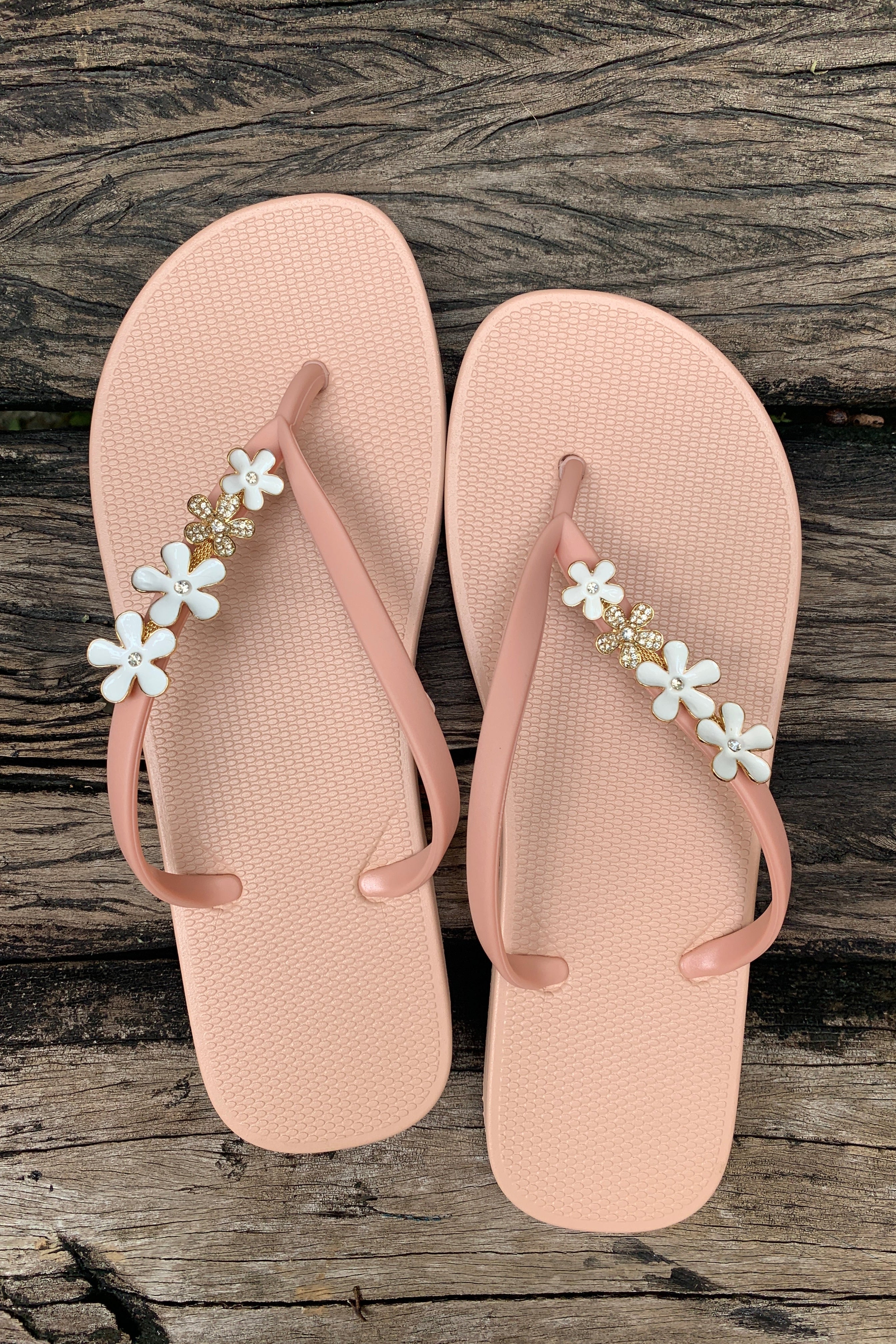 a pair of pink flipflops with pink flowers as decorative charms on straps