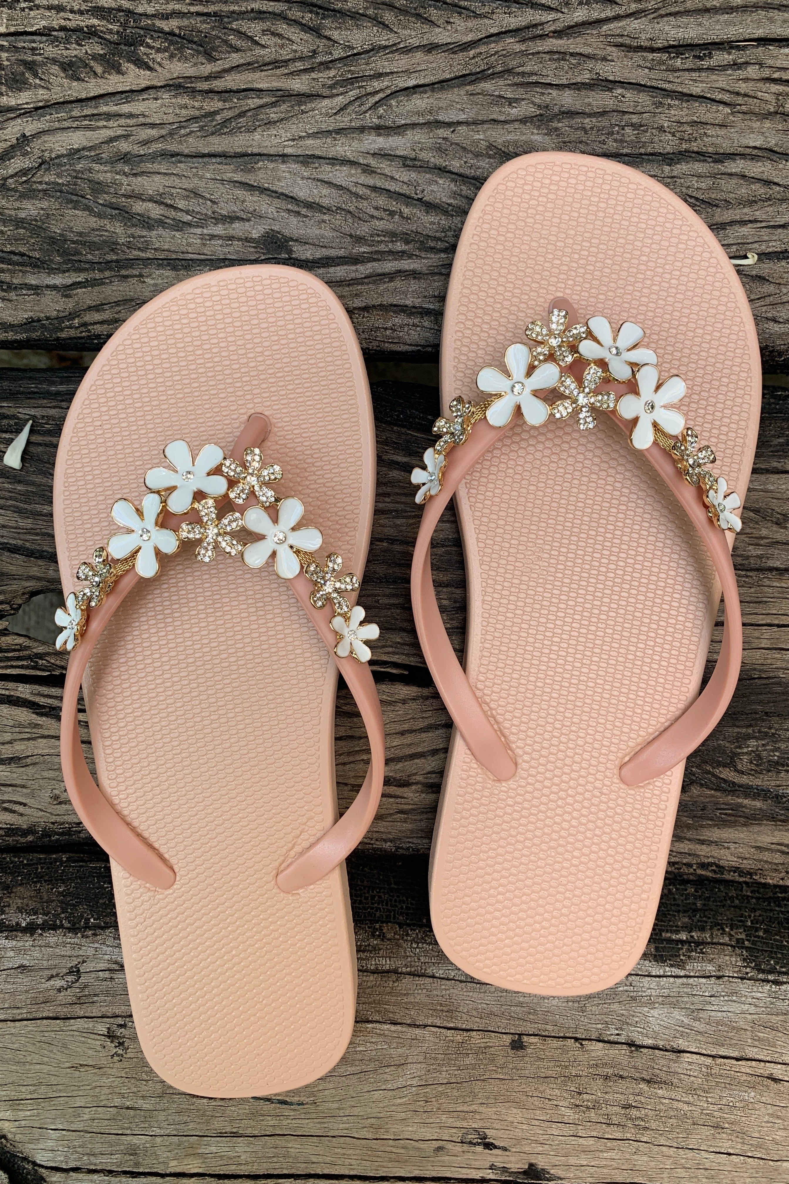 a pair of pink flipflops with white flower arch design charm with rhinestones