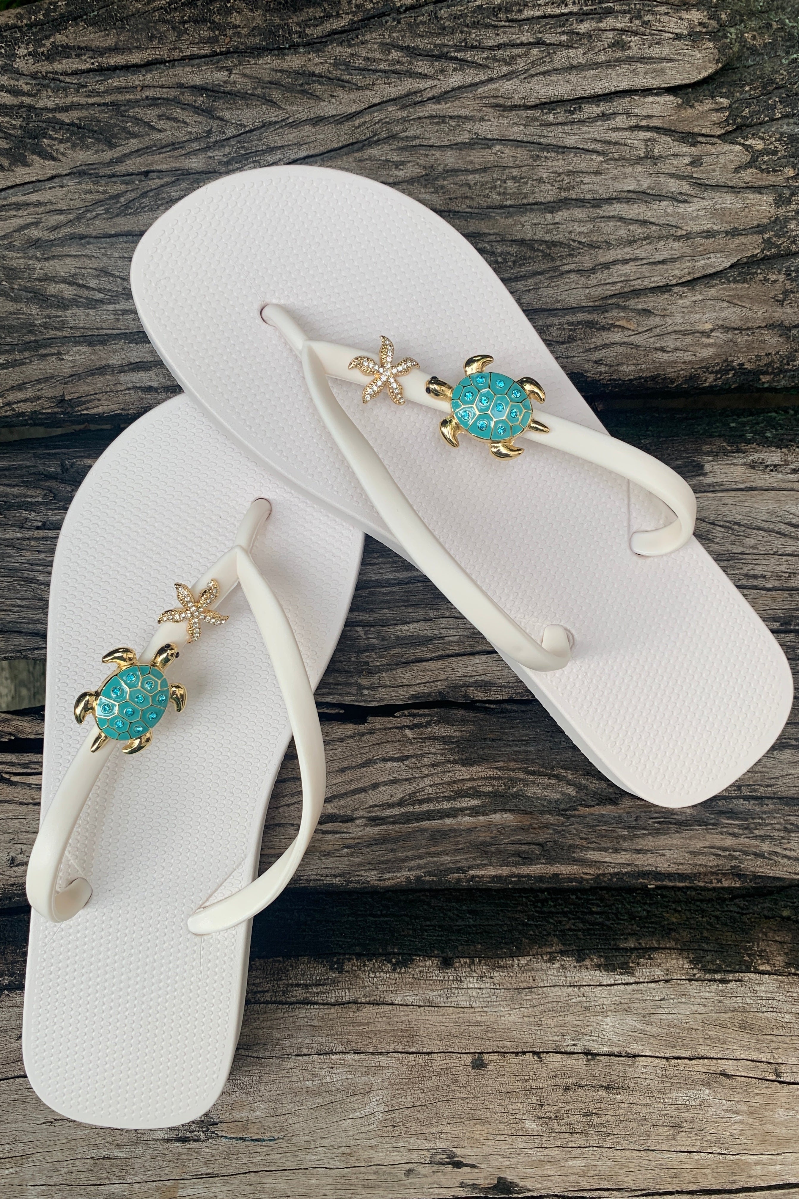 White flip-flops with starfish and turtle charms on straps