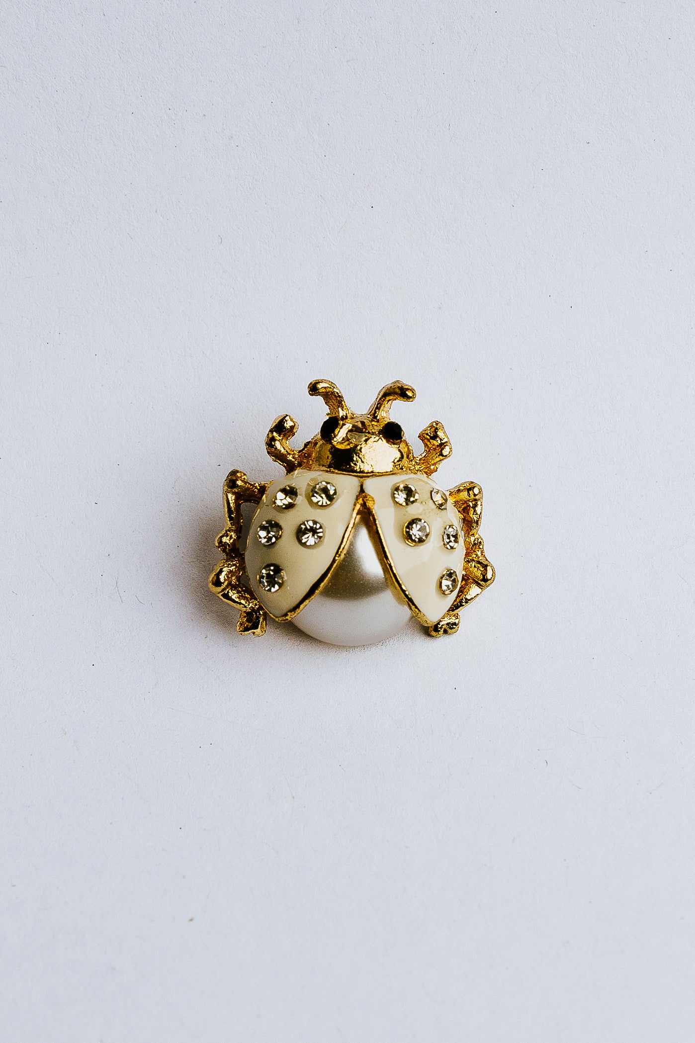 Gold and pearl beetle-shaped charm on a white background