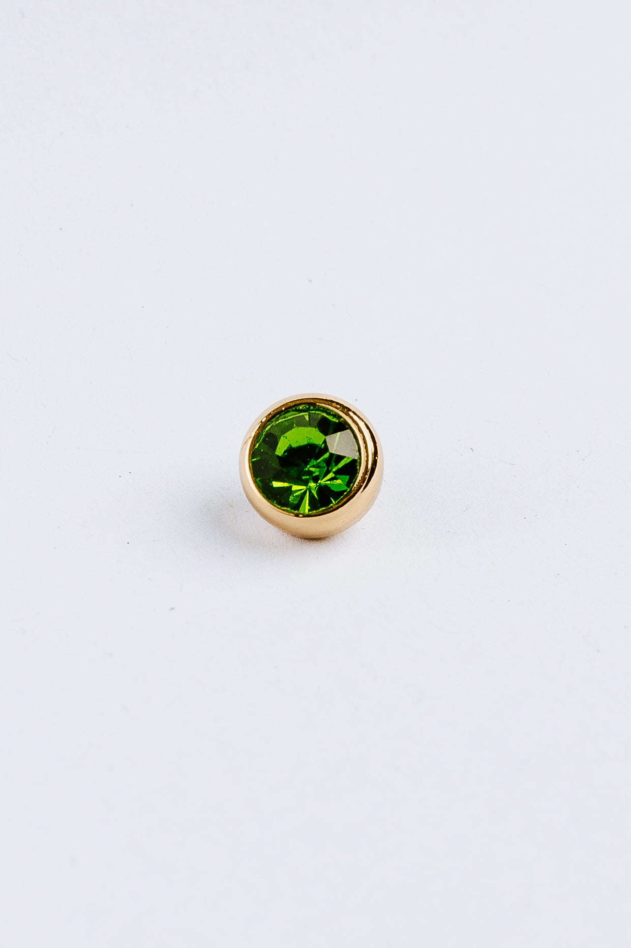 Green gemstone in gold on a white background