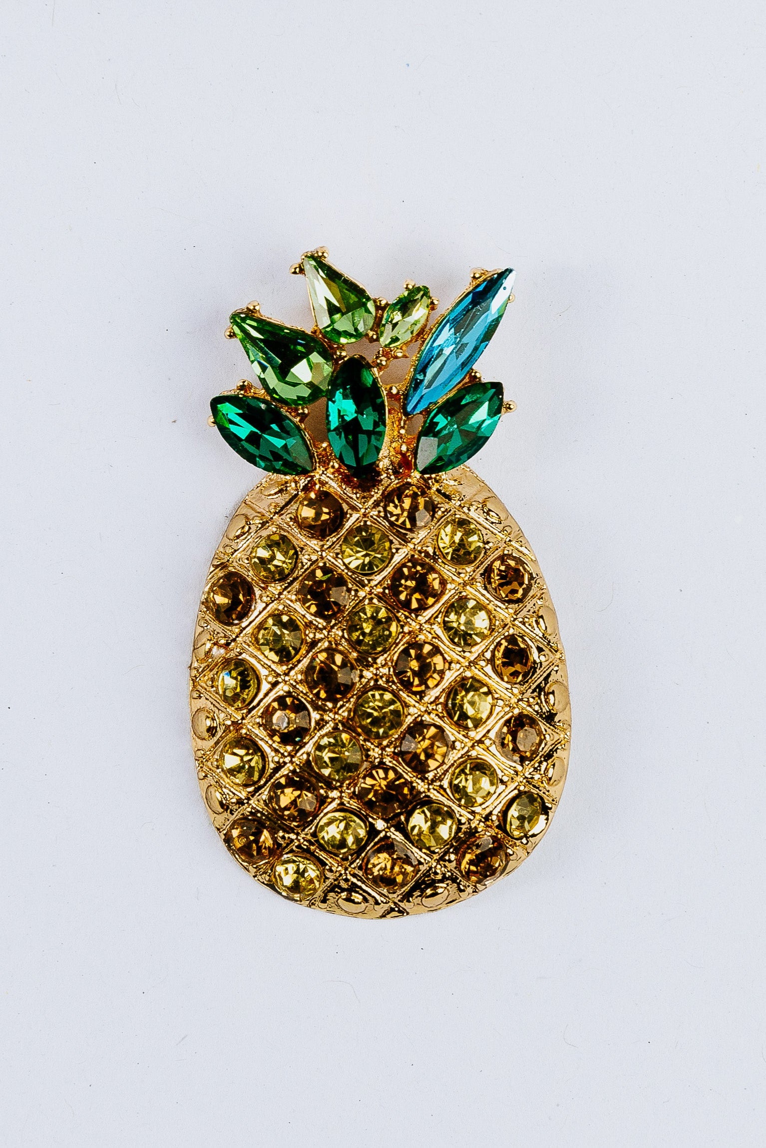 Gold pineapple charm with green leaves and a blue gem on a white background