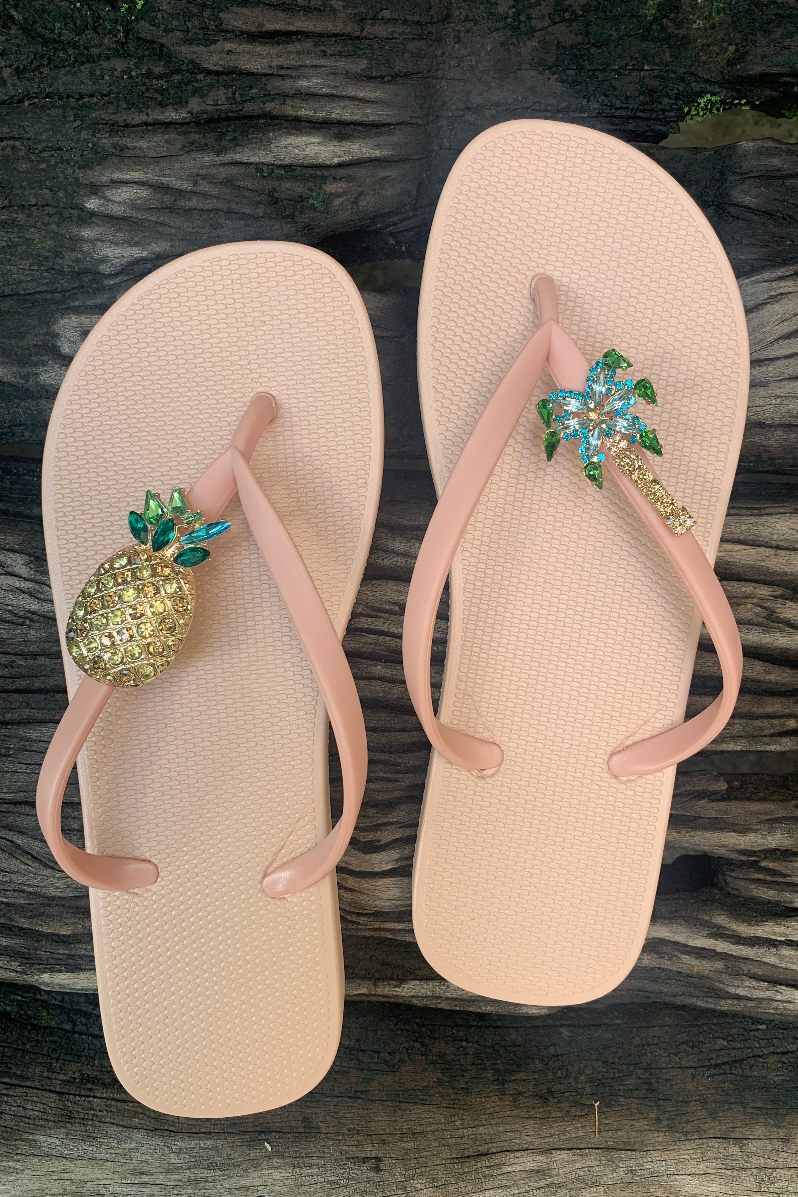 Pink flip-flops with decorative pineapple and palm tree embellishments 