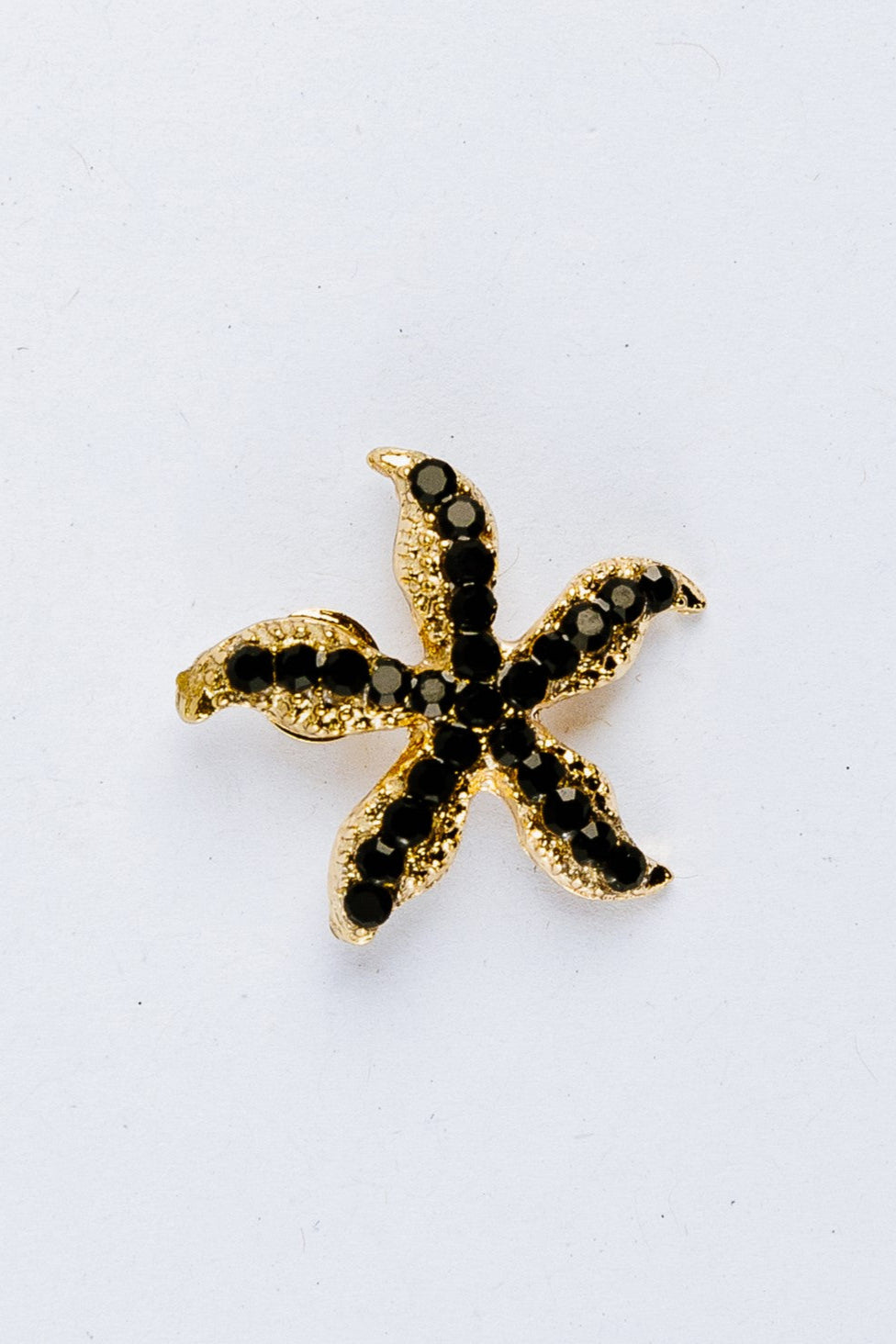 Starfish-shaped charm with black gemstones on a white background