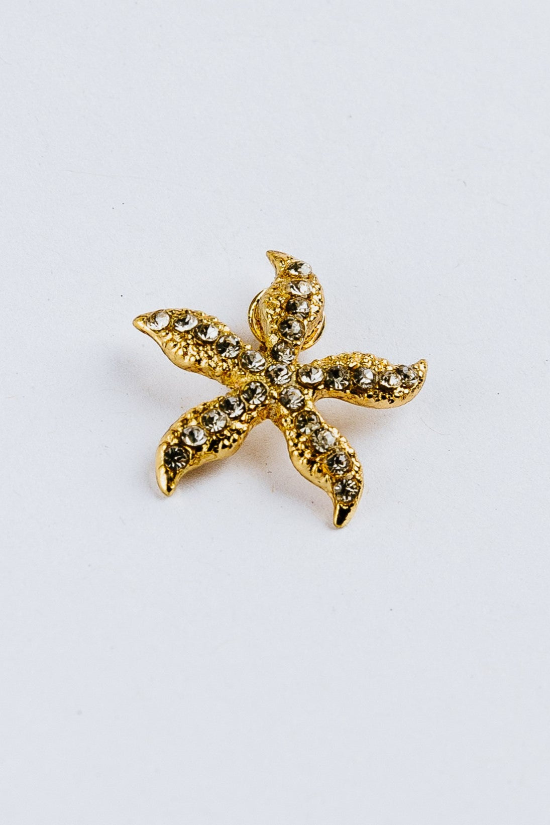 Gold starfish-shaped charm with rhinestones on a white background