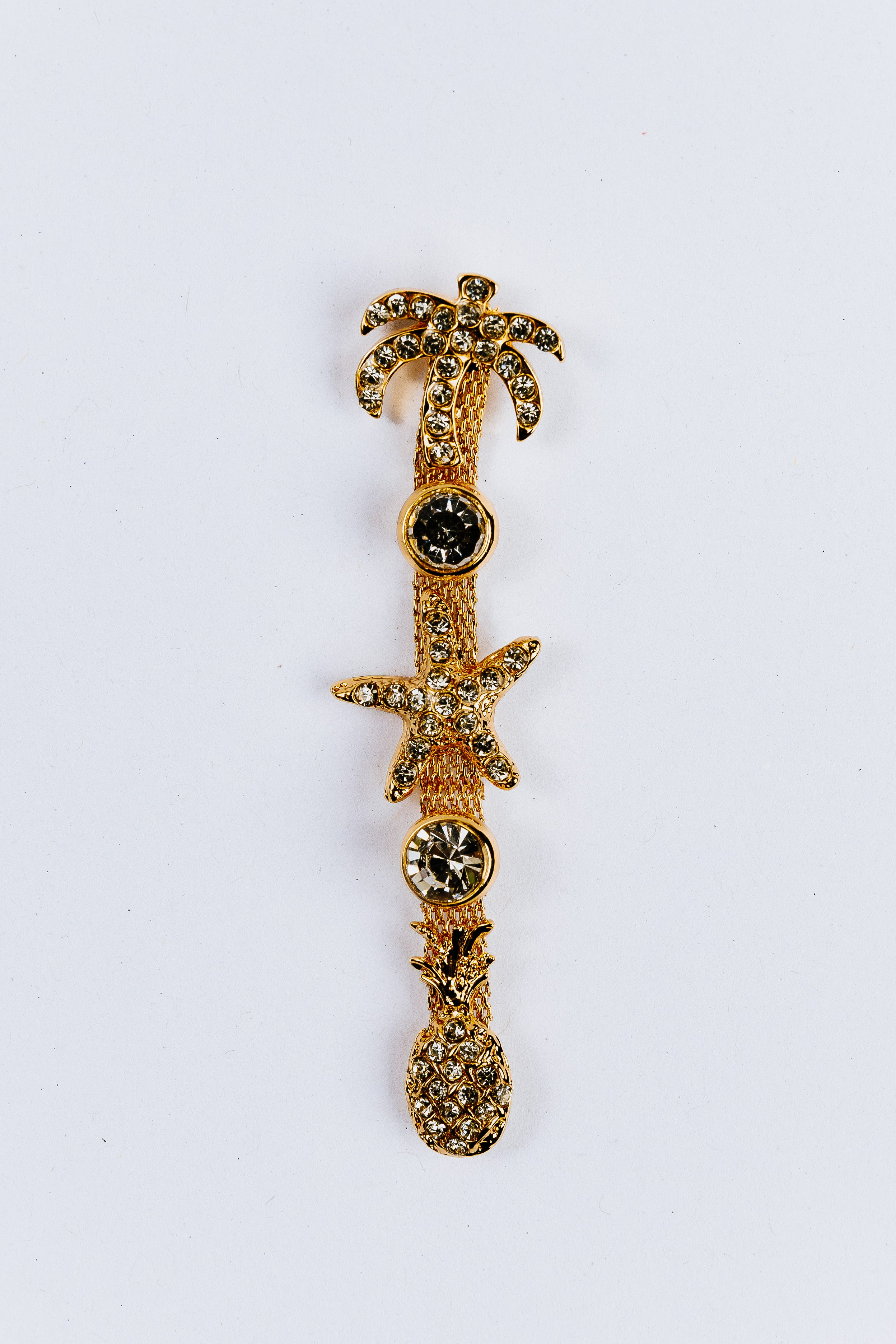Decorative charm with palm tree, starfish, and pineapple design on a white background