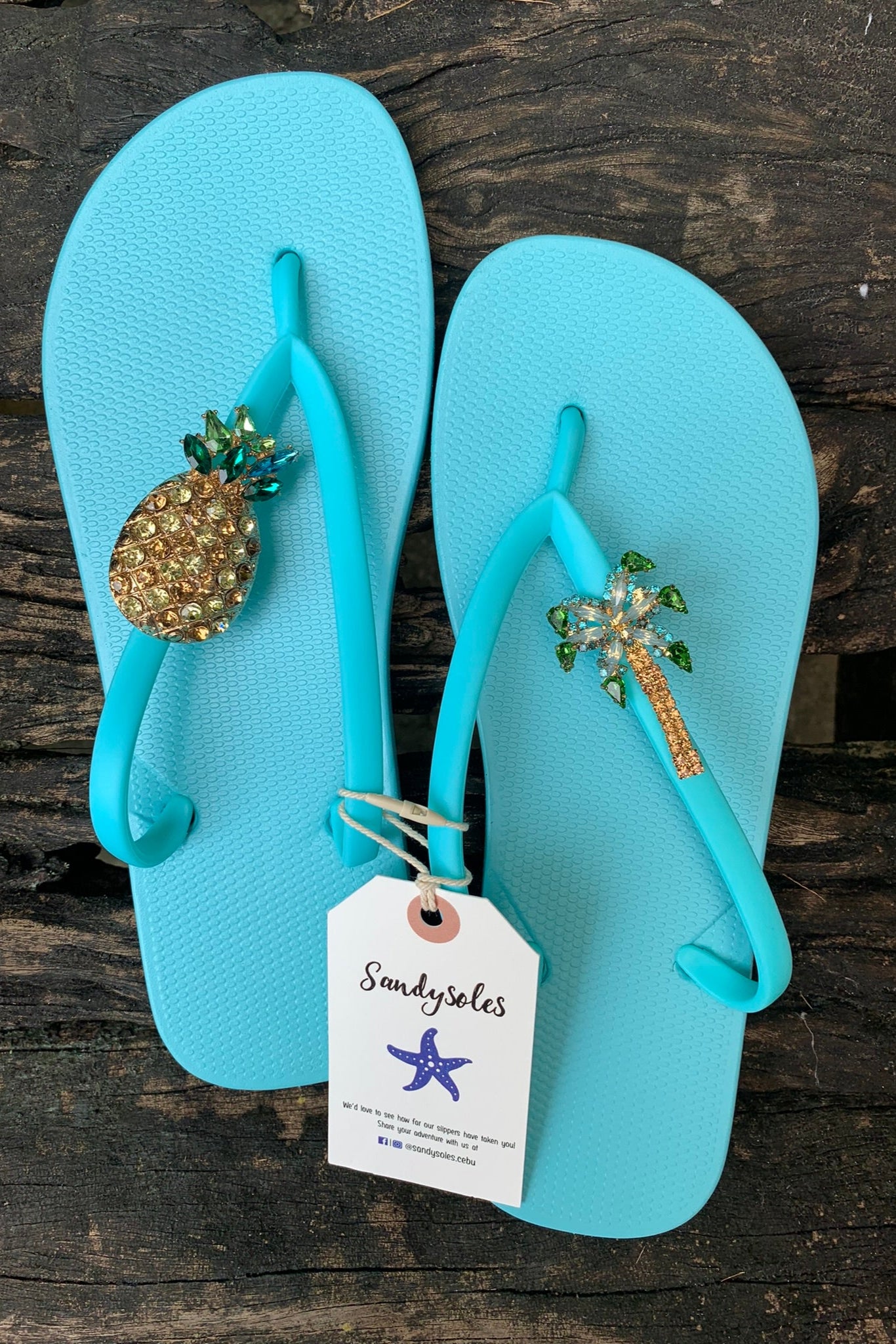 a pair of aqua flipflops with decorative charms