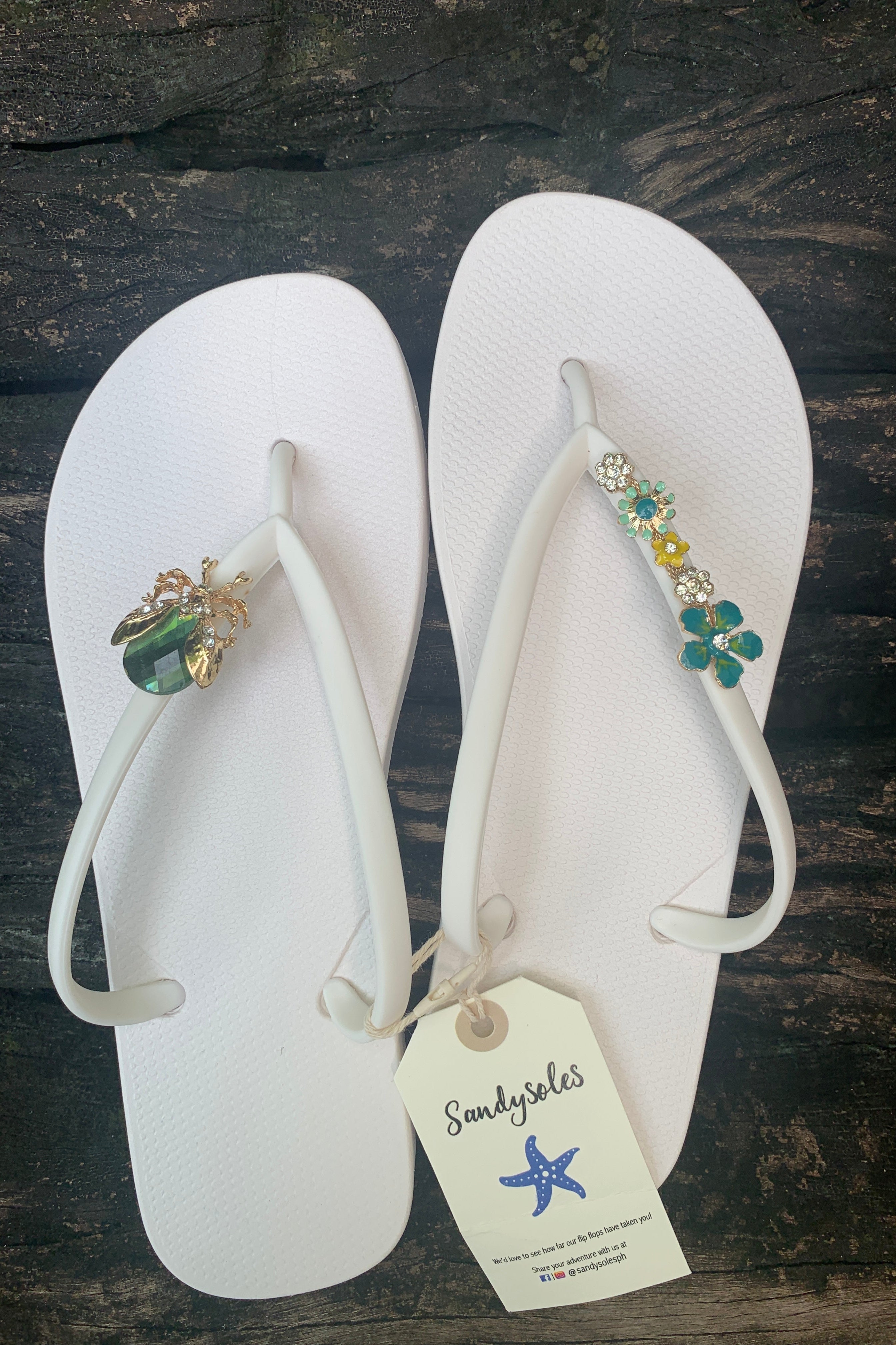 Pair of white flip-flops with decorative charms on straps 