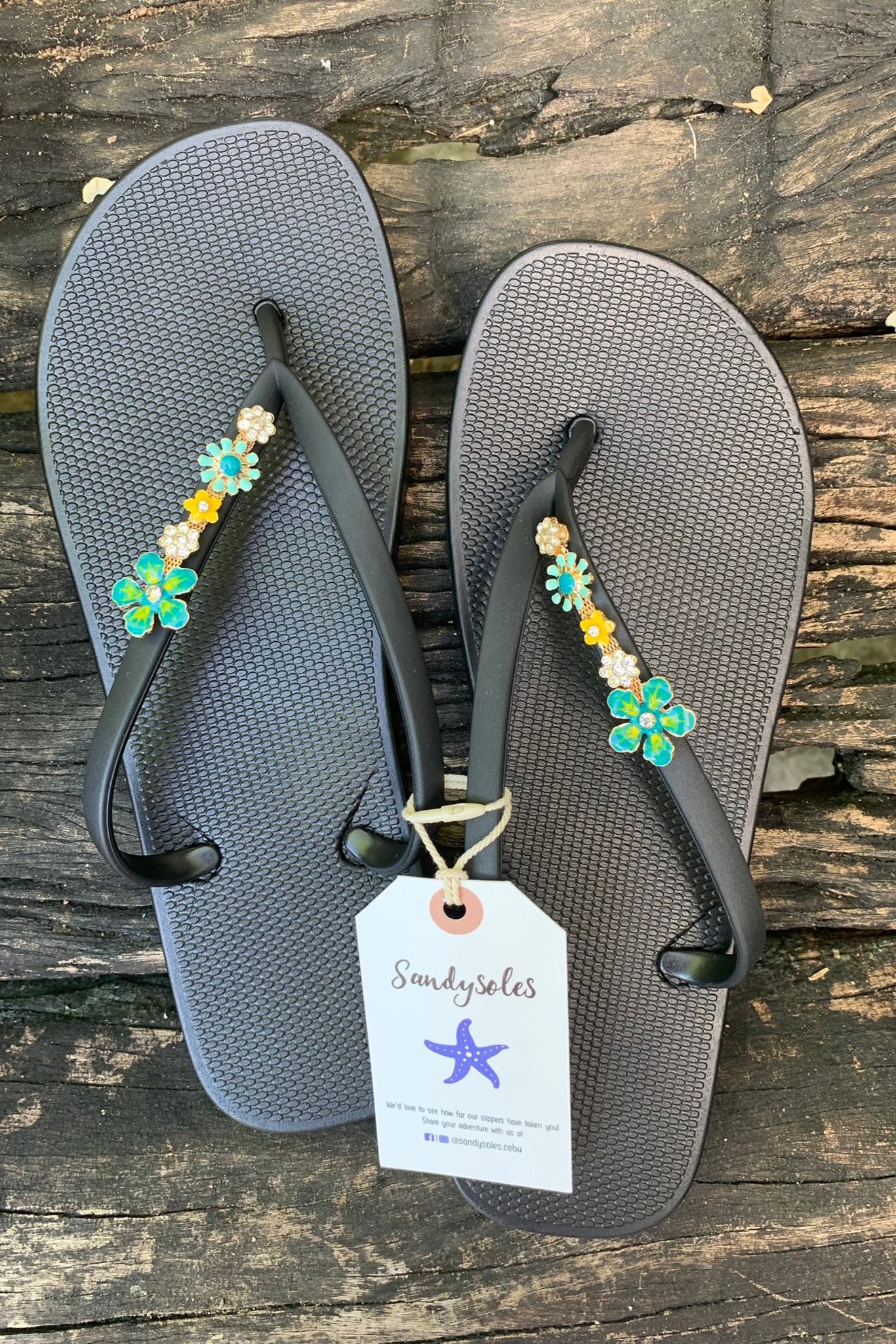 black flip-flops with decorative green flower charms 