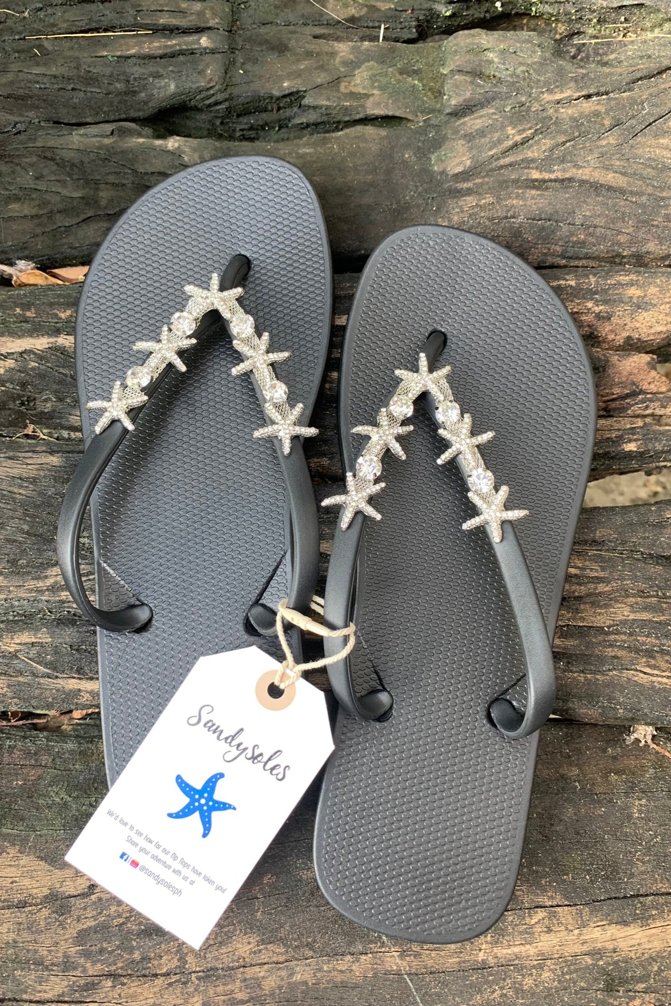 a pair of black flip-flops with a silver twin starfish arch charm