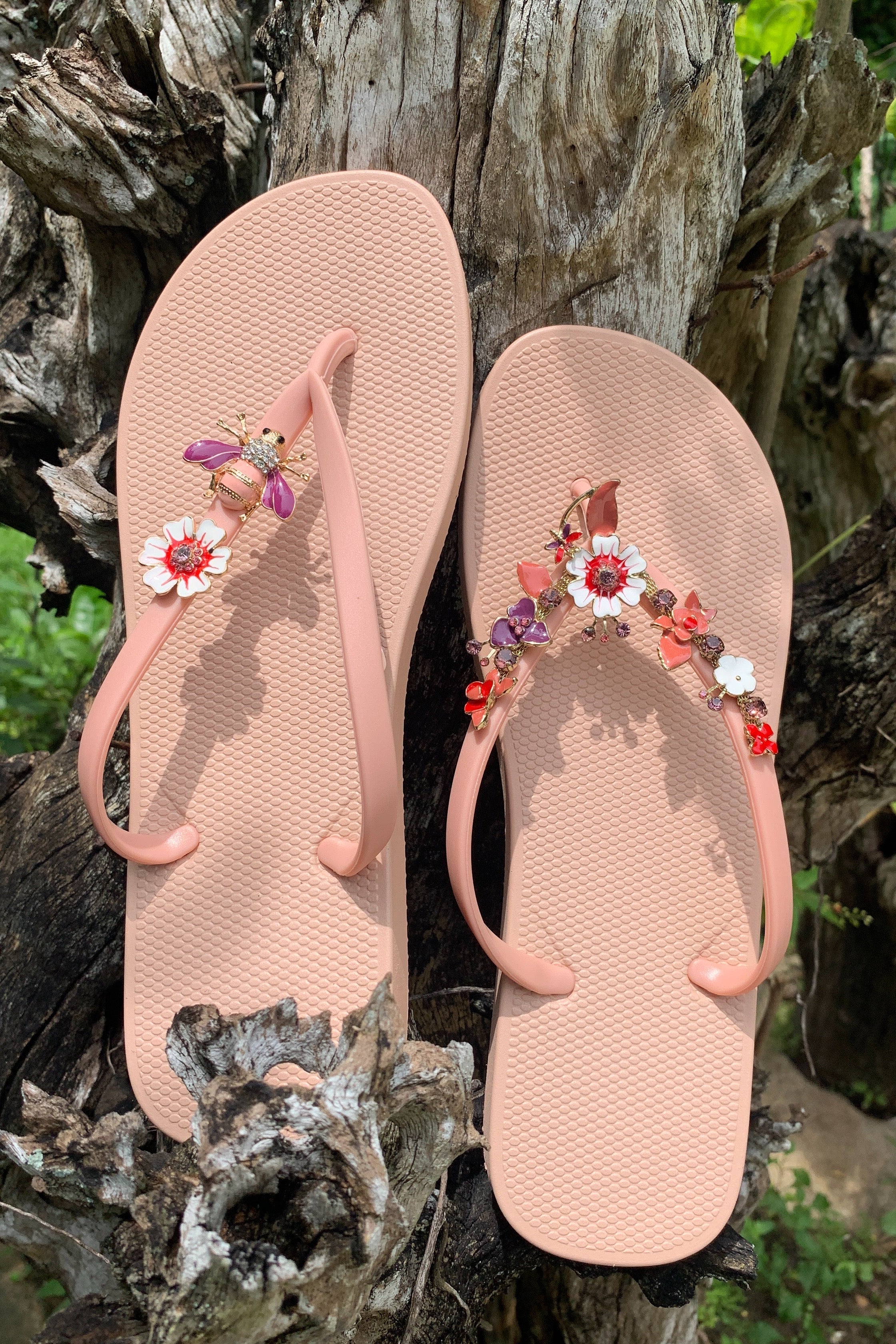 Pair of pink flip-flops with floral decorations on a natural background