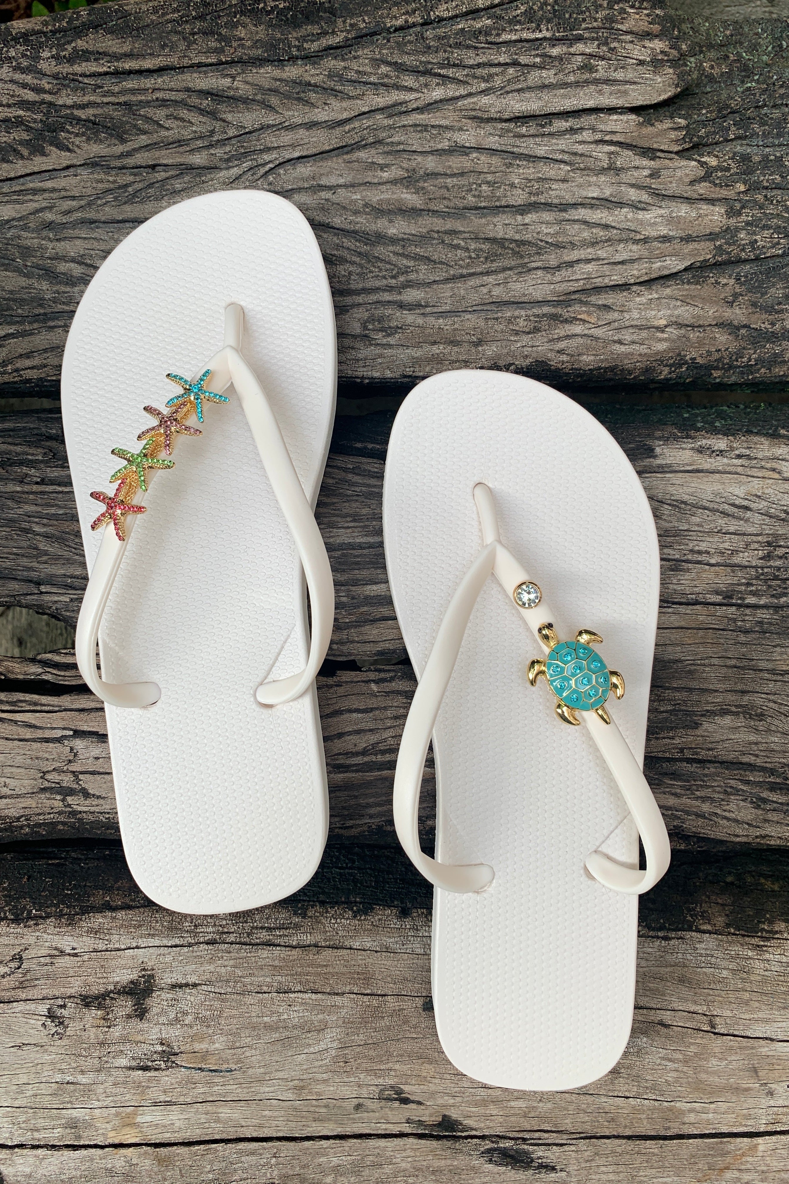 White flip-flops with starfish, turtle and gem decorative charms on straps 