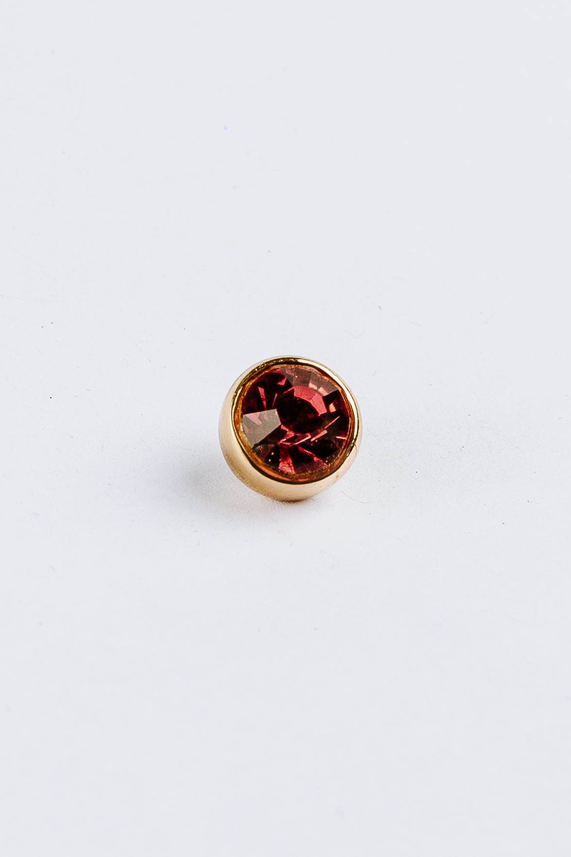 Pink gemstone in gold charm on a white background