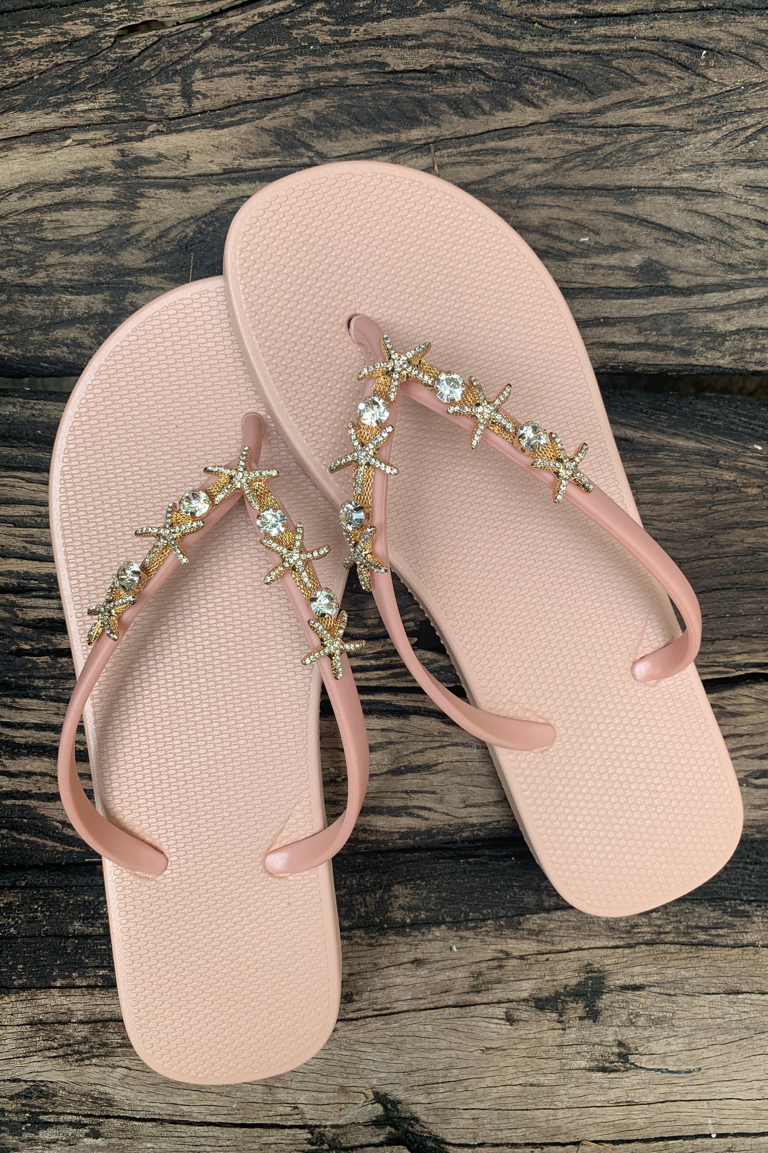 a pair of pink flip-flops with golden twin starfish arch charm