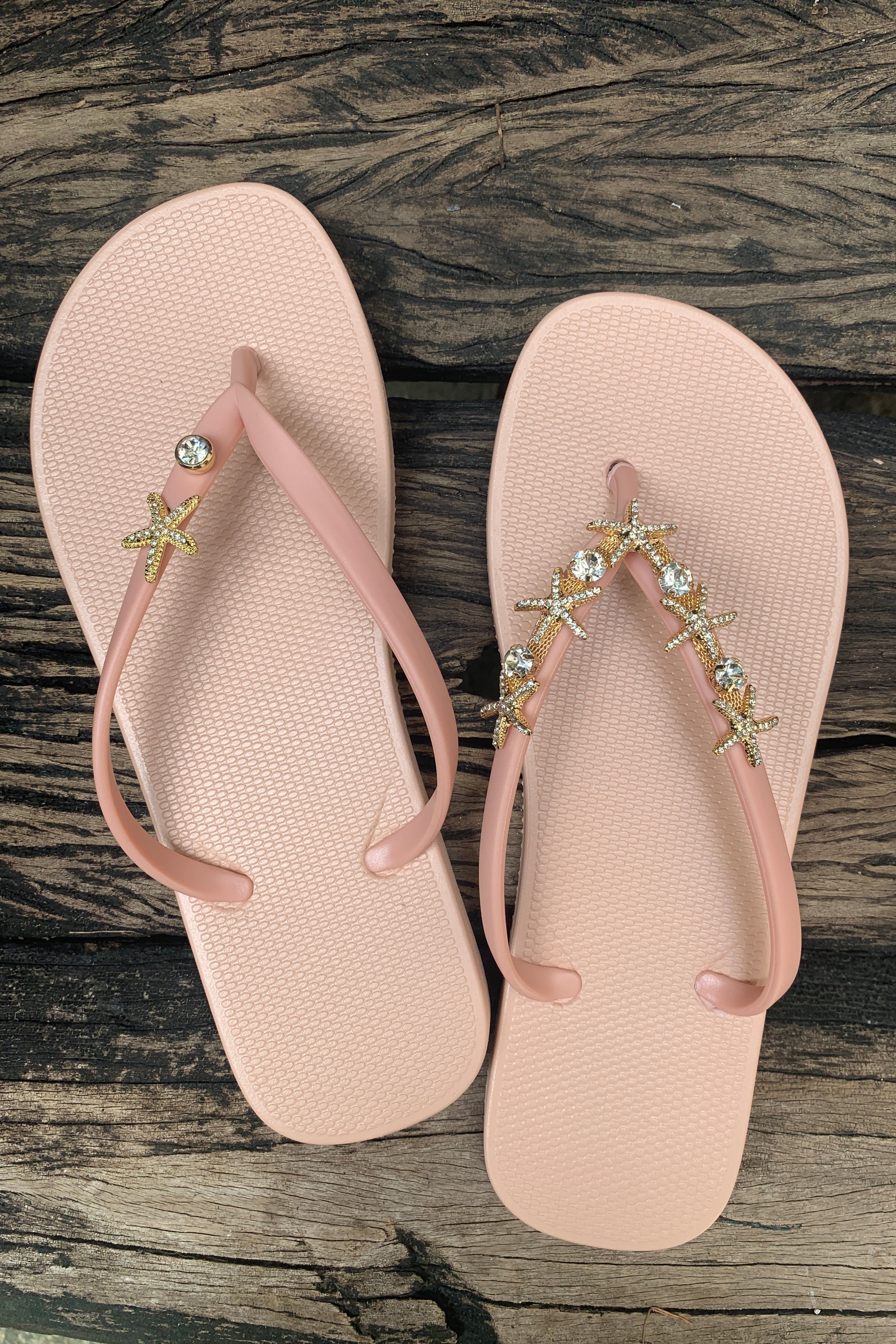 a pair of pink flip-flops with starfish arch-shaped charm with rhinestones in gold