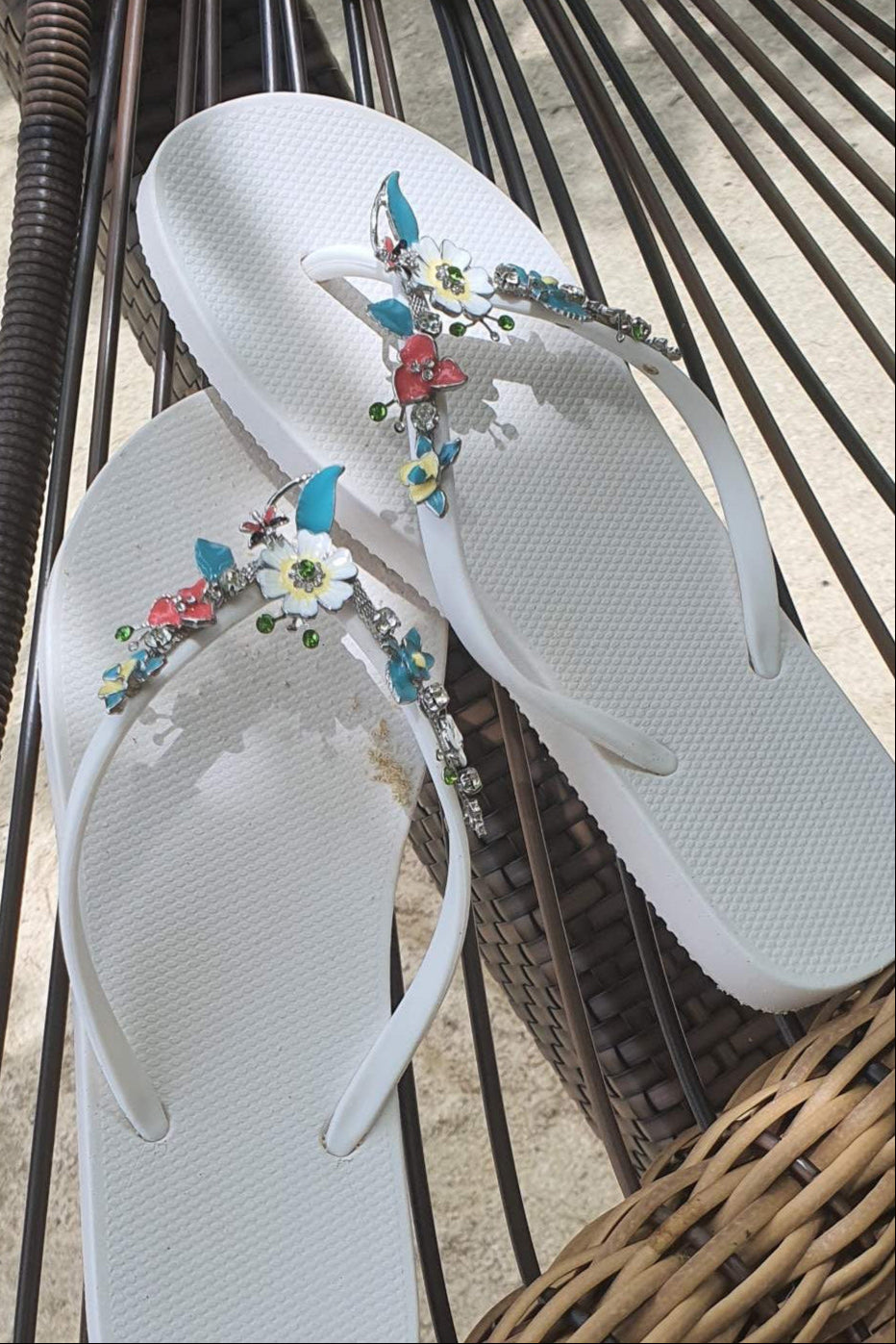 a pair of white flipflops with blue flower arch design charm with rhinestones